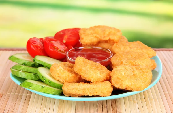 Fried chicken nuggets with vegetables and sauce on table in park — Stock Photo, Image