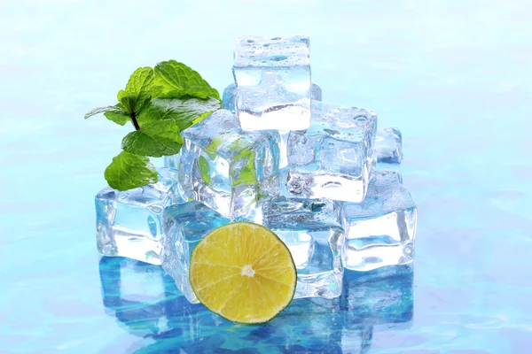 Cubos de gelo com hortelã e limão sobre fundo azul claro — Fotografia de Stock