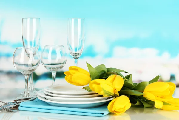 Amarelo tulipas e utensílios para servir em fundo natural azul — Fotografia de Stock