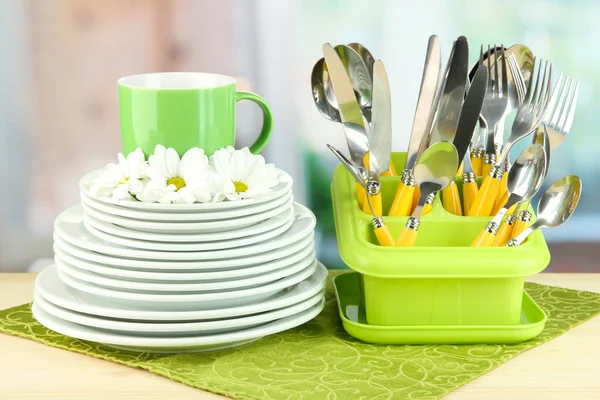 Πιάτα, πιρούνια, μαχαίρια, κουτάλια και άλλα σκεύη κουζίνας σε χαρτοπετσέτα χρώμα, σε φωτεινό φόντο — Φωτογραφία Αρχείου