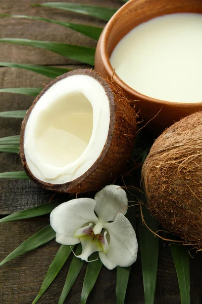 Noce di cocco con foglie e fiori, su fondo grigio in legno — Foto Stock