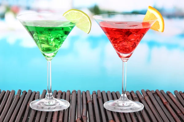 Glasses of cocktails on table near pool — Stock Photo, Image