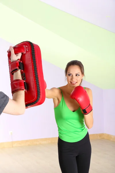 Jovem mulher bonita com luvas de boxe no treino, no ginásio — Fotografia de Stock