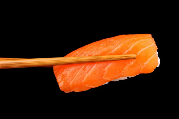 Hålla sushi med pinnar isolerade på svart — Stockfoto