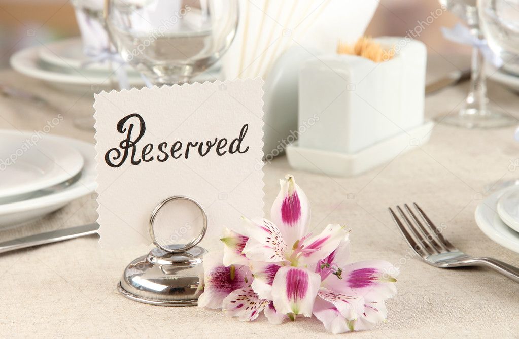 Reserved sign on restaurant table with empty dishes and glasses