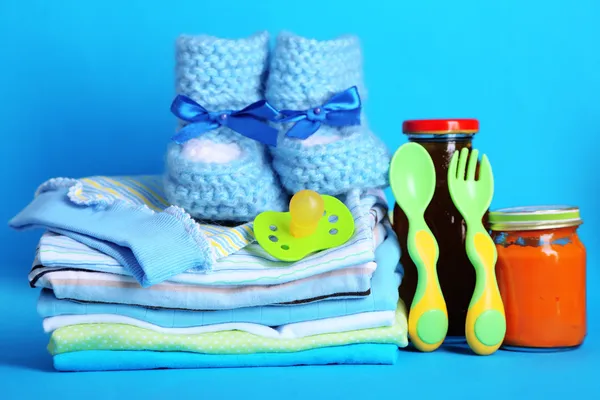 Pile of baby clothes on blue background — Stock Photo, Image