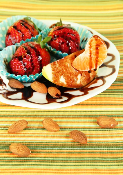 Fruit in chocolate on plate on tablecloth close-up — Stock Photo, Image