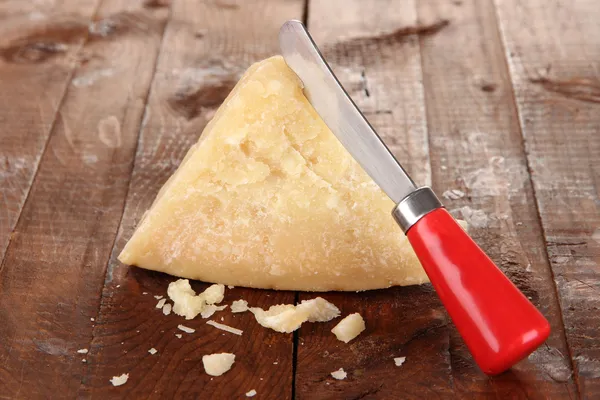 Pedazo de queso parmesano con cuchillo en la mesa de madera — Foto de Stock