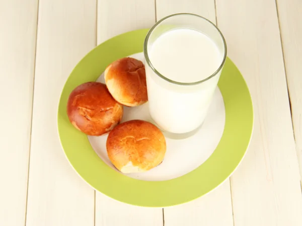 Хлебные рулеты и стакан молока на деревянном столе — стоковое фото