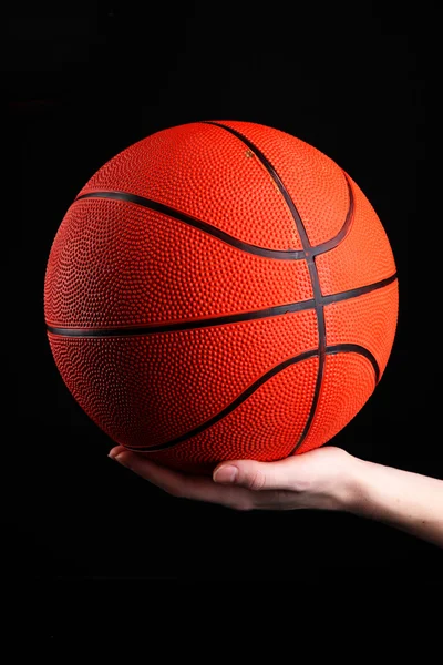 Basketbal in vrouw de hand op zwarte achtergrond — Stockfoto