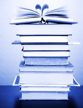Stack of interesting books and magazines on wooden table on green background clipart
