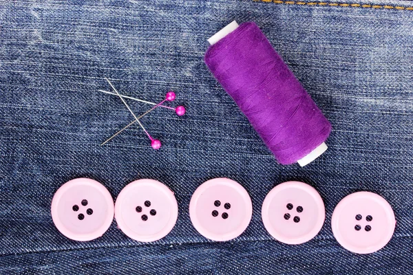 Colorful sewing buttons with thread on jeans closeup — Stock Photo, Image