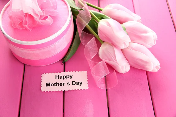 Beautiful bouquet of tulips and gift for Mother's Day on pink wooden background — Stock Photo, Image