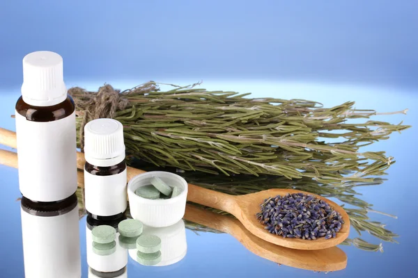 Frascos de medicamentos y hierbas sobre fondo azul. concepto de homeopatía — Foto de Stock