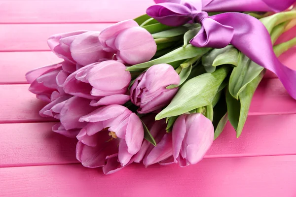 Belo buquê de tulipas roxas no fundo de madeira rosa — Fotografia de Stock