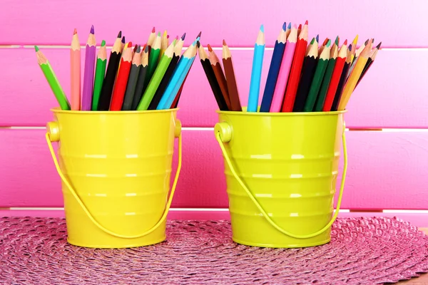 Lápices de colores en dos cubos sobre la mesa sobre fondo rosa —  Fotos de Stock