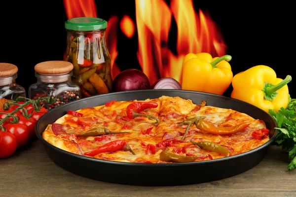 Вкусная пицца пепперони в кастрюле с овощами на фоне пламени — стоковое фото