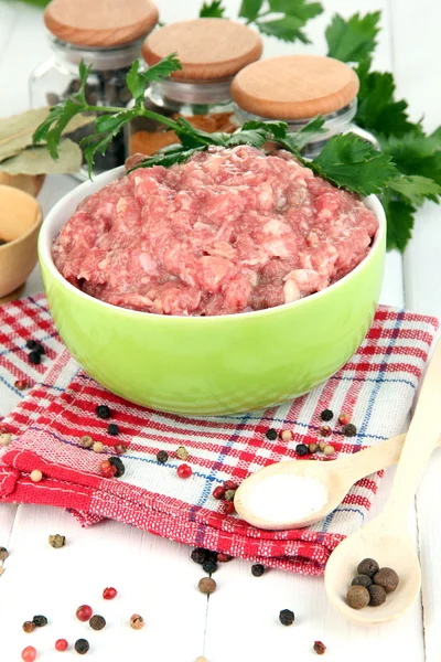 Schüssel mit rohem Hackfleisch mit Gewürzen auf Holztisch — Stockfoto