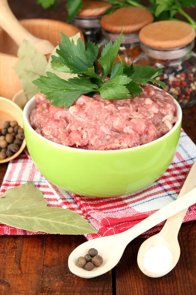 Schüssel mit rohem Hackfleisch mit Gewürzen auf Holztisch — Stockfoto