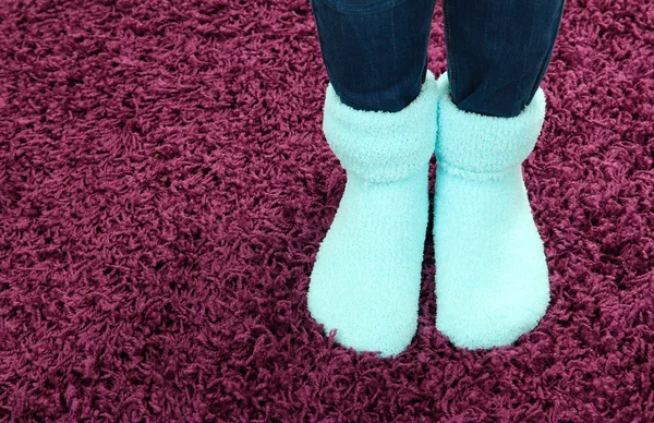 Patas femeninas en calcetines de colores sobre fondo de alfombra de color —  Fotos de Stock