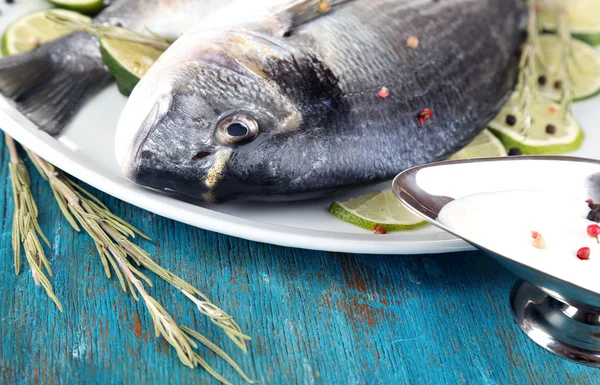 Two fish dorado with lemon on plate on blue wooden table close-up — Stock Photo, Image