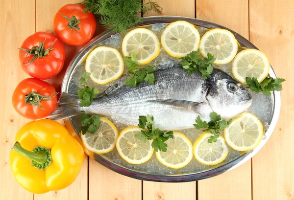 Fresh fish of dorado on tray with lemon and parsley on wooden table — Stock Photo, Image