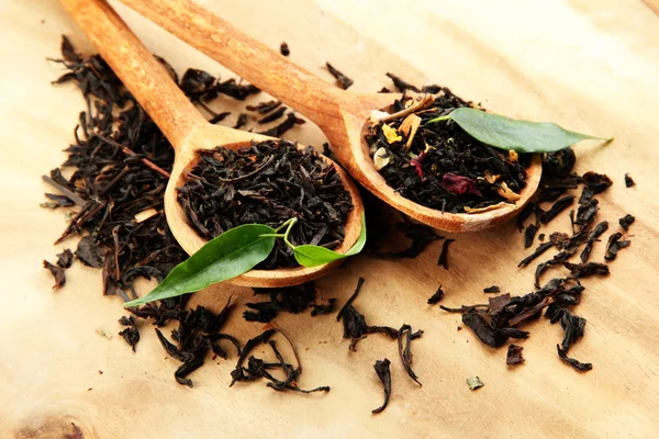 Suchej herbaty z zielonych liści w drewniane łyżki, na tle drewniane — Zdjęcie stockowe