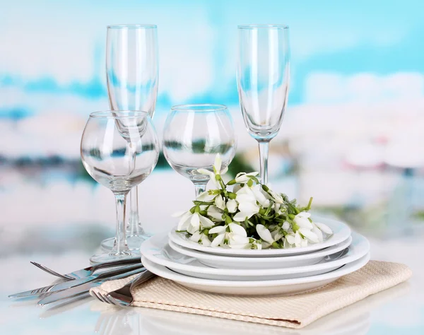Serving dishes and snowdrops on blue natural background — Stock Photo, Image