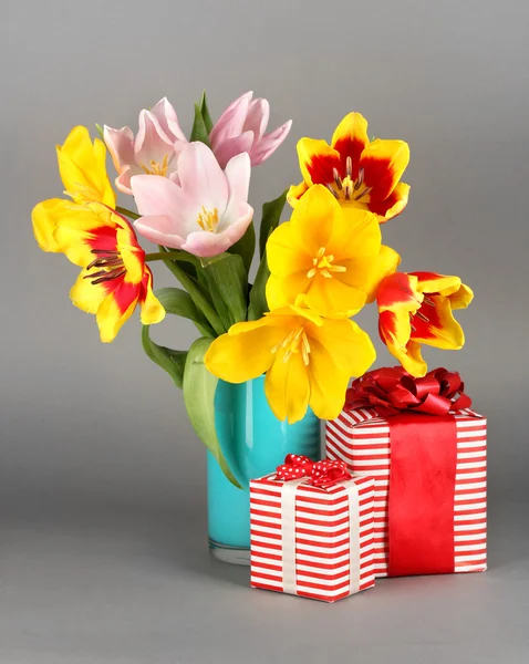 Beautiful tulips in bucket with gifts on grey background — Stock Photo, Image