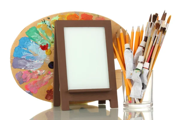 Photo frame as easel with artist's tools isolated on white — Stock Photo, Image