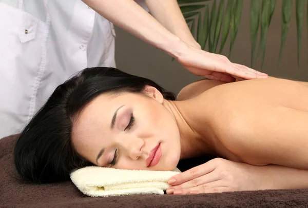 Beautiful young woman in spa salon getting massage, on dark background — Stock Photo, Image