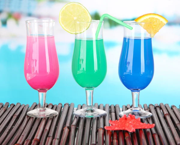 Glasses of cocktails on table near pool — Stock Photo, Image