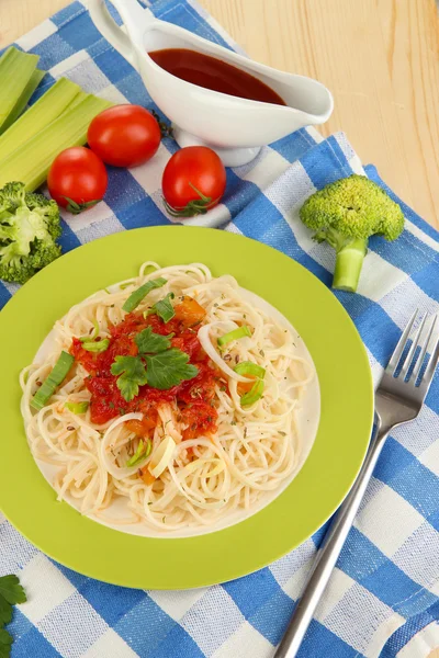 Spaghetti saporiti con salsa e verdure su piatto su tavolo di legno primo piano — Foto Stock