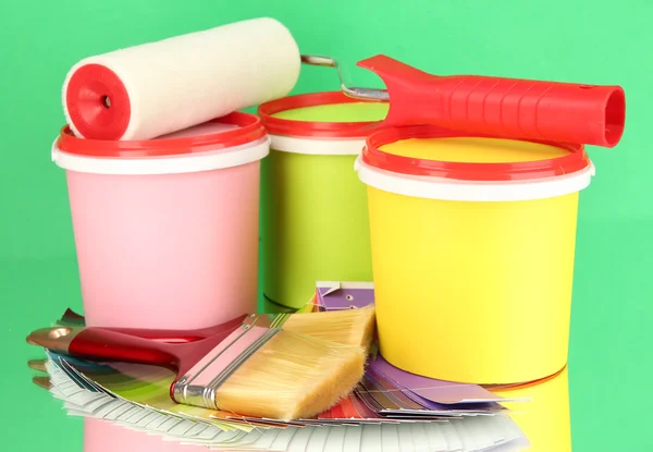 Set for painting: paint pots, brushes, paint-roller, palette of colors on green background — Stock Photo, Image