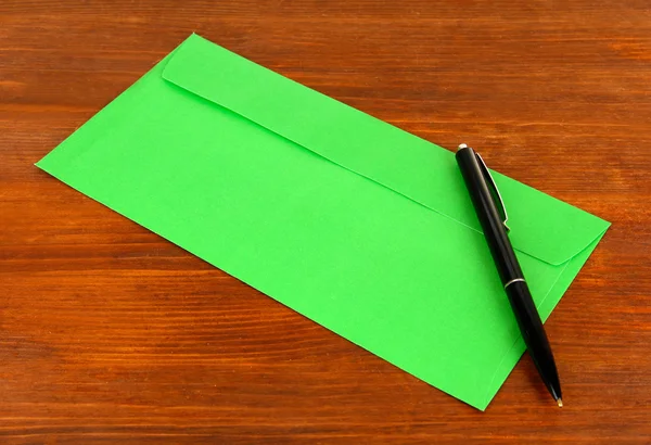 Envelope com caneta sobre fundo de madeira — Fotografia de Stock