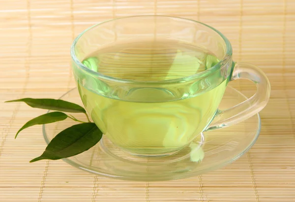 Xícara transparente de chá verde no tapete de bambu, close-up — Fotografia de Stock