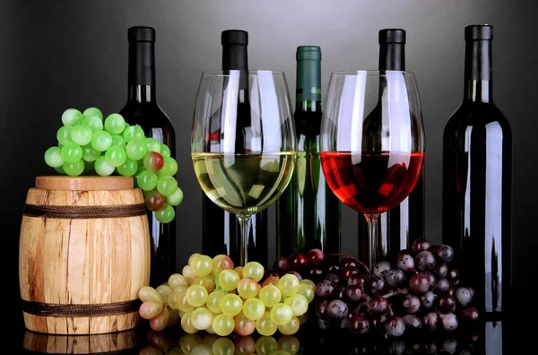 Assortimento di vino in calici e bottiglie su fondo grigio — Foto Stock