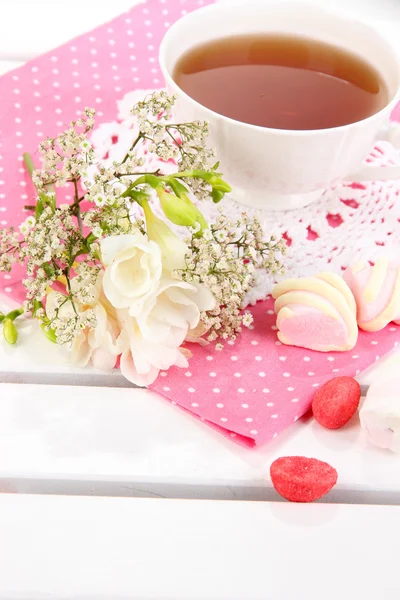 Beautiful composition with cup of tea and flowers on wooden picnic table close-up — Stock Photo, Image