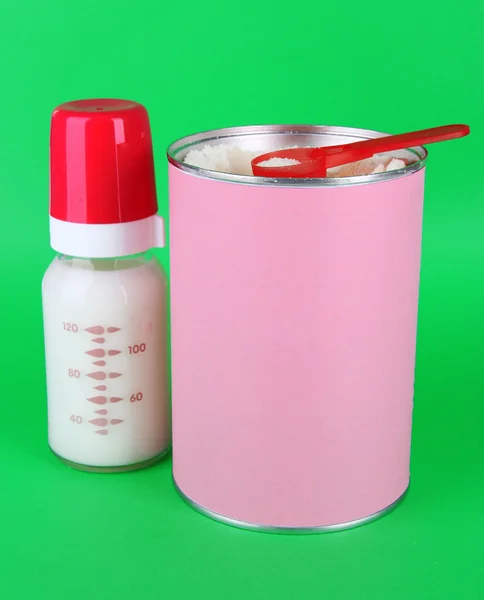 Sproszkowane mleko z butelki mleka na zielony deseń — Zdjęcie stockowe