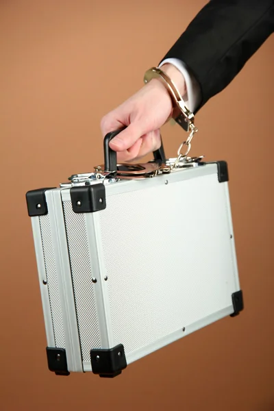 Hand with handcuff and suitcase, on color background — Stock Photo, Image