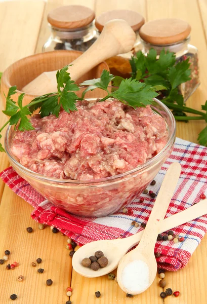 Tigela de carne moída crua com especiarias na mesa de madeira — Fotografia de Stock