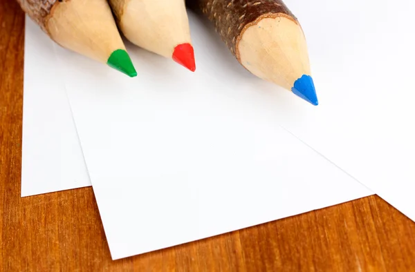 Lápices de madera coloridos con hojas de papel sobre mesa de madera — Foto de Stock