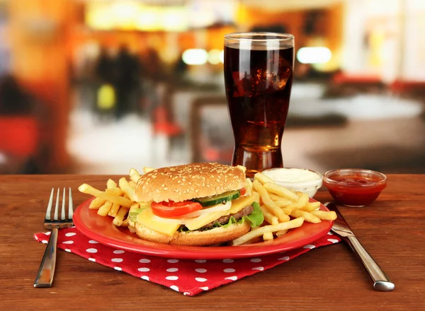 Gustoso cheeseburger con patate fritte e bevanda fredda, su sfondo brillante — Foto Stock