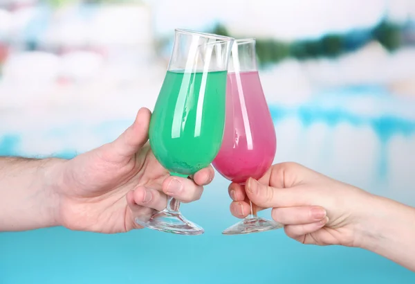 Cocktail nelle mani di uomini e donne sullo sfondo della piscina — Foto Stock