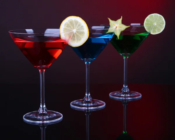 Alkoholische Cocktails in Martinigläsern auf dunkelrotem Hintergrund — Stockfoto
