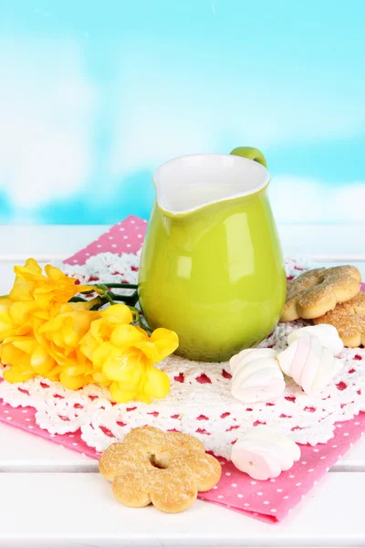 Mooie compositie van melk en koekjes op houten picknicktafel op natuurlijke achtergrond — Stockfoto