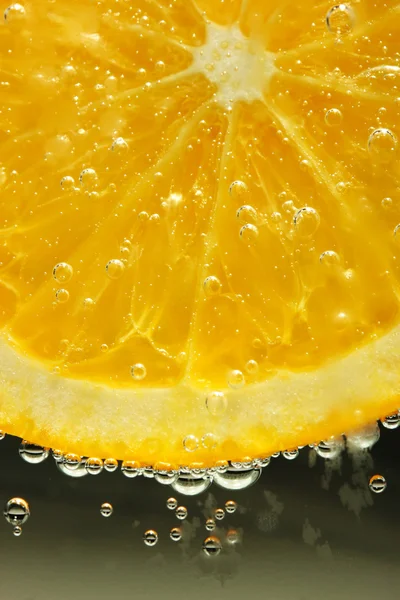 Slice of orange in the water with bubbles, on black background — Stock Photo, Image
