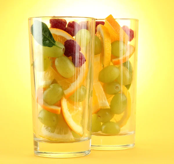 Transparent glas med citrusfrukter, på gul bakgrund — Stockfoto