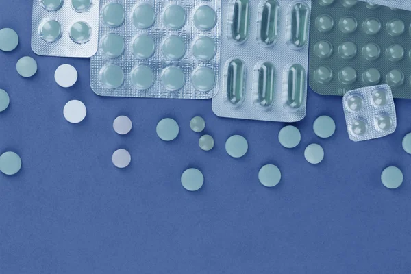 Kapslar och tabletter förpackade i blåsor i blått ljus — Stockfoto