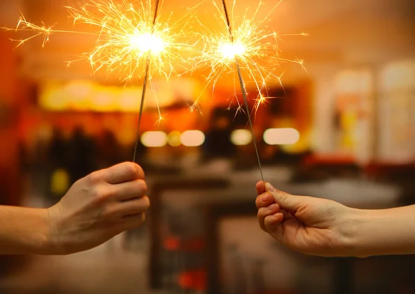 Beautiful sparklers in woman hands on room backgroun — ストック写真